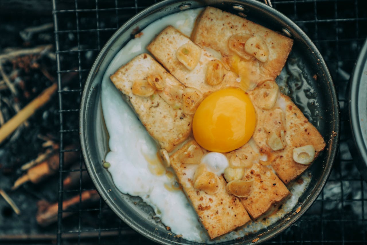Top view of yummy toasts with garlic frying under egg on pan on barbecue grid