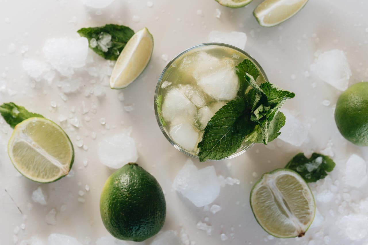 Top view of a refreshing mojito with lime and mint, surrounded by ice cubes.