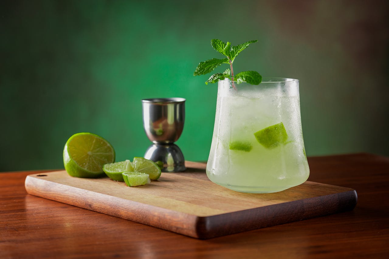 Chilled lemonade with fresh lime and mint garnish on a wooden board, perfect for a summer refreshment.